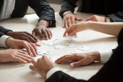 Collaboration d’une équipe de managers assemblant des pièces de puzzle pour structurer le management et les soft skills