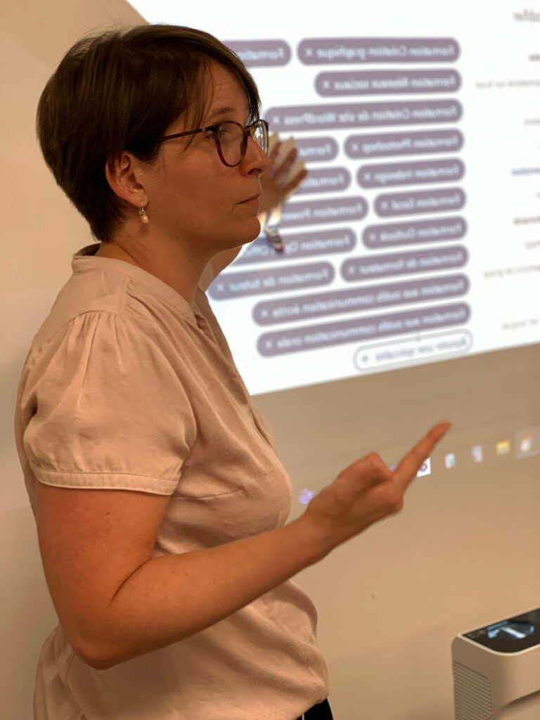 Caroline Dauvergne présentant des contenus de formation devant un écran lors d’un atelier avec des formateurs
