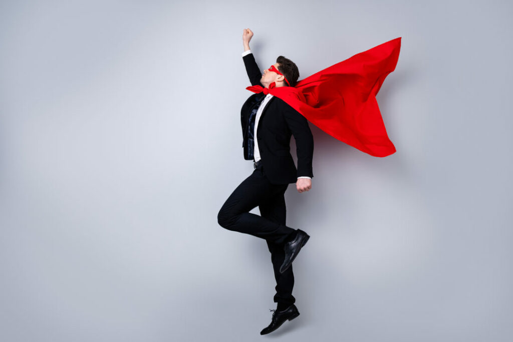 Professionnel en costume avec cape rouge illustrant avec humour la posture du formateur